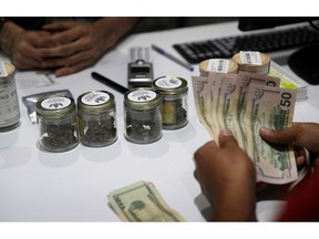 FILE - In this July 1, 2017, file photo, a person buys marijuana at the Essence cannabis dispensary in Las Vegas. The first full year of legalized marijuana for recreational use in Nevada pushed taxable pot sales past the $500 million mark statewide and raised nearly $70 million in tax revenue, including $27.5 million for schools. A marijuana trade group says pot production, processing and sales could be a billion-dollar industry in Nevada by 2024. That's a key finding in an economic analysis being released Friday, Oct. 26, 2018, by the Nevada Dispensary Association.