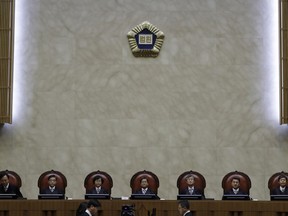 South Korean Chief Justice of the Supreme Court KIM Myeongsu, center, sits with other justices upon their arrival at the Supreme Court in Seoul, South Korea, Tuesday, Oct. 30, 2018. South Korea's Supreme Court has ruled that a Japanese steelmaker should compensate four South Koreans for forced labor during Japan's colonial rule of the Korean Peninsula before the end of World War II.