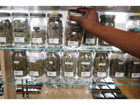 In this Tuesday, Oct. 2, 2018, photo, a clerk reaches for a container of marijuana buds for a customer at Utopia Gardens, a medical marijuana dispensary, in Detroit. Michigan and North Dakota, where voters previously authorized medical marijuana, will decide now if the drug should be legal for any adult 21 and older. They would become the 10th and 11th states to legalize so-called recreational marijuana since 2012.