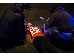 People gather to tend to a protester lying on the ground after a truck collided with into protesters calling for the right to form unions Tuesday, Oct. 2, 2018, in Flint, Mich. Police said the collision appears to be an accident.