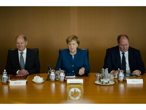 German Chancellor Angela Merkel sits between Vice-chancellor and Finance Minister Olaf Scholz, left, Head of Chancellery and Minister for Special Tasks Helge Braun, right, as she leads the weekly cabinet meeting of the German government at the chancellery in Berlin, Wednesday, Oct. 24, 2018.