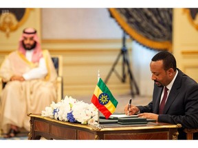 FILE - In this Sunday, Sept. 16, 2018 file photo released by the state-run Saudi Press Agency, Ethiopia's Prime Minister Abiy Ahmed, right, signs a peace accord with Eritrea as Saudi Crown Prince Mohammed bin Salman looks on in the distance in Jiddah, Saudi Arabia. Whether pressured to speak up after receiving assistance or making a diplomatic play for more, some African countries are expressing support for Saudi Arabia as shocking details in the killing of Jamal Khashoggi approached a crescendo, with South Sudan issuing a rare statement praising the Saudi position to defuse the crisis as "honorable".