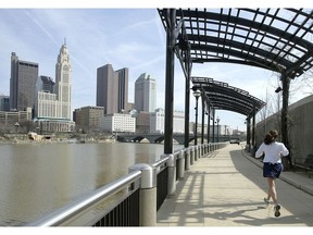 FILE - In this March 15, 2004, file photo, a woman runs the Franklinton floodwall next to the Scioto River in Columbus, Ohio. The largest city named for Christopher Columbus has called off its observance of the holiday named for the explorer. Offices in Columbus, Ohio, will remain open Monday, Oct. 8, 2018, and close on Veterans Day instead.