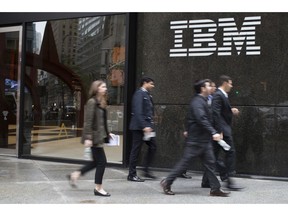 FILE- In this April 26, 2017, file photo, pedestrians walk past the IBM logo displayed on the IBM building in New York. Shares of Red Hat skyrocketed at the opening bell Monday, Oct. 29, 2018, after IBM, in the biggest acquisition in its 100-year history, acquired the software company.