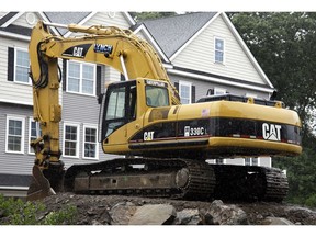 FILE- In this July 24, 2017, file photo, a Caterpillar excavator rests at a housing construction site in North Andover, Mass. Caterpillar Inc. reports earnings Tuesday, Oct. 23, 2018.