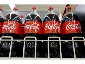 FILE- In this Aug. 8, 2018, file photo bottles of Coca-Cola sit on a shelf in a market in Pittsburgh. The Coca-Cola Co. reports earnings Tuesday, Oct. 30.