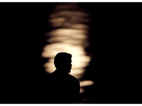 FILE- In this June 27, 2018, file photo a man is silhouetted against moonlight reflecting off the Missouri River as he watches the full moon rise beyond downtown buildings in Kansas City, Mo. A by the Associated Press-NORC Center for Public Affairs Research and MTV found that half of 15 to 26-year olds think they will eventually be better off than their parents in terms of household finances. About 29 percent expect to do as well as their parents and 20 percent expect to be worse off.