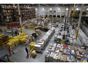 FILE- In this Aug. 3, 2017, file photo, workers prepare to move products at an Amazon fulfillment center in Baltimore. Amazon's announcement Tuesday, Oct. 2, 2018, that it will raise its minimum wage to $15 an hour will intensify the pressure on other companies to also lift their pay levels, particularly retailers and warehouse operators that are looking to staff up for the holidays.