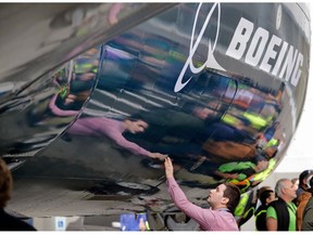 FILE - In this Feb. 5, 2018, file photo, Boeing worker Paul Covaci reaches out to touch a Boeing 737 MAX 7, the newest version of Boeing's fastest-selling airplane, during a debut for employees and media of the new jet in Renton, Wash. Boeing Co. reports earnings Wednesday, Oct. 24.