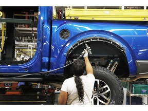 FILE- In this Sept. 27, 2018, file photo a United Auto Workers assemblyman works on a 2018 Ford F-150 truck being assembled at the Ford Rouge assembly plant in Dearborn, Mich. Ford Motor Co. reports earnings Wednesday, Oct. 24.