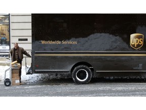 FILE- In this Jan. 5, 2018, photo, a UPS delivery driver loads his cart with packages from his truck, in Boston. UPS Inc. reports earnings Wednesday, Oct. 24.