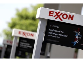 FILE- This April 25, 2017, file photo, shows Exxon service station signs in Nashville, Tenn. New York's attorney general is suing Exxon Mobil saying the company misled investors about the risks climate change posed to its business.