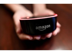 FILE- In this Aug. 16, 2018, file photo a child holds his Amazon Echo Dot in Kennesaw, Ga. Amazon.com Inc. reports earnings Thursday, Oct. 25.