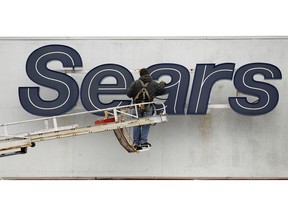 FILE - In this Feb. 13, 2012 file photo, a worker repairs a sign outside the Sears Grand store in Solon, Ohio. Sears has filed for Chapter 11 bankruptcy protection Monday, Oct. 15, 2018, buckling under its massive debt load and staggering losses. The company once dominated the American landscape, but whether a smaller Sears can be viable remains in question.
