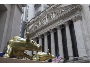 FILE- In this April 24, 2018, file photo replicas of Arturo Di Modica's "Charging Bull" are for sale on a street vendor's table outside the New York Stock Exchange. The U.S. stock market opens at 9:30 a.m. EDT on Monday, Oct. 22.