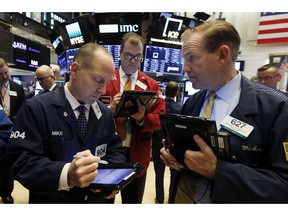 FILE- In this Monday, Oct. 22, 2018, file photo traders Michael Urkonis, left, William Lawrence, center, and Michael Smyth work on the floor of the New York Stock Exchange. The U.S. stock market opens at 9:30 a.m. EDT on Friday, Oct. 26.