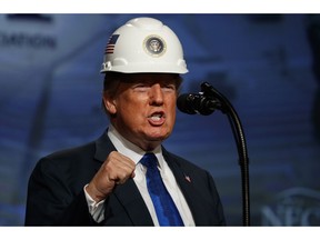 President Donald Trump pumps his fist after putting on a hard hat given to him before speaking to the National Electrical Contractors Association Convention at the Pennsylvania Convention Center, Tuesday, Oct. 2, 2018, in Philadelphia.
