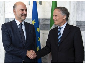 Italian Minister of Foreign Affairs and International Cooperation Enzo Moavero Milanesi, right, shakes hands with EU Commissioner for Economic and Monetary Affairs Pierre Moscovici on the occasion of their meeting at the Foreign Ministry Farnesina Palace in Rome, Friday, Oct. 19, 2018. Italy's financial markets are shaken following the European Union's stinging rebuke of the new populist government's budget bill, which pushes the deficit far beyond previously agreed levels.