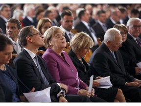 German Chancellor Angela Merkel, front 3rd left, looks up as she arrives for an ecumenical mass at the Berlin cathedral during the Unification Day public festival in Berlin, Germany, Wednesday, Oct. 3, 2018.