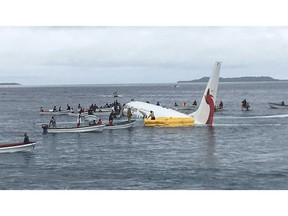 FILE - In this Sept. 28, 2018, file photo, local fishing boats move in to recover the passengers and crew of Air Niugini flight following the plane crashing into the sea on its approach to Chuuk International Airport in the Federated States of Micronesia. The airline operating a flight that crashed into a Pacific lagoon on Friday in Micronesia now says that one man is missing, after earlier saying that all 47 passengers and crew had safely evacuated the sinking plane.