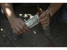 An Iranian street money exchanger holds a U.S. banknote in downtown Tehran, Iran, Tuesday, Oct. 2, 2018. Iran's currency, the rial, unexpectedly rallied Tuesday after weeks of depreciation following President Donald Trump's decision to withdraw America from Tehran's nuclear deal with world powers, sending Iranians rushing to exchange shops to cash in.