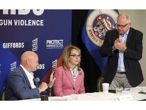 In this Oct. 26, 2018 photo, Minnesota gubernatorial candidate, Democrat Tim Walz, right, applauds as Capt. Mark Kelly, left, introduces his wife, former Rep. Gabby Giffords as they hosted a roundtable against gun violence in Minneapolis. The 2018 election marks the first time that groups supporting gun control measures could spend more on a campaign than the National Rifle Association.