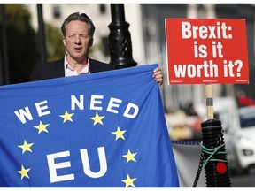 A pro-EU demonstrator holds up an EU flag to oncoming traffic outside the Palace of Westminster as the British government holds a cabinet meeting on Brexit inside 10 Downing Street, London, Tuesday, Oct. 16, 2018.  The Brexit agreement must be sealed in the coming weeks to leave enough time for relevant parliaments to ratify it, but talks continue, particularly over how to ensure no physical border dividing the UK from Northern Ireland and the EU member state of Ireland.
