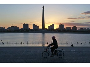 In this Saturday, Oct. 27, 2018 photo, a man rides his electric bike as the Tower of the Juche Idea is silhouetted agains the sunrise in Pyongyang, North Korea. North Korea is exploring a grand plan to become a regional transportation hub, inspired in part by the successes of Singapore and Switzerland, and would be open to joining world financial institutions such as the International Monetary Fund if current member states give up their "hostile" policies toward it, a senior government economist has told The Associated Press.