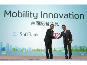 Representative Director and CTO of SoftBank Corp. Junichi Miyakawa, left and Executive Vice President of Toyota Motor Corporation Shigeki Tomoyama, right, shake hands during a press conference in Tokyo Thursday, Oct. 4, 2018. Japan's No. 1 automaker Toyota Motor Corp. and Japanese technology giant SoftBank Group Corp. say they are setting up a joint venture to create mobility services.