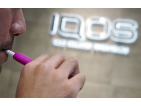 In this Oct. 22, 2018 photo, a visitor tries out an iQOS at a store in Tokyo. While New York-based Philip Morris is hoping to woo the world with its penlike "heat-not-burn" device iQOS (EYE-kose) as a better option than old-style smoking, nowhere else has it scored greater success than in Japan.