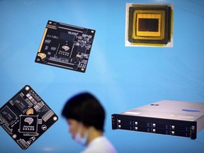 In this May 18, 2018, photo, a visitor walks past a display showing microchips and circuit boards at the 21st China Beijing International High-tech Expo in Beijing. The Trump administration imposed restrictions on technology exports to a Chinese semiconductor maker on Monday, Oct. 29, 2018, citing national security grounds amid a mounting tariff battle with Beijing.