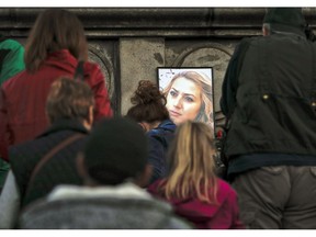 A portrait of slain television reporter Viktoria Marinova is placed on the Liberty Monument, as people wait to place flowers and candles during a vigil in Ruse, Bulgaria, Monday, Oct. 8, 2018. Bulgarian police are investigating the rape, beating and slaying of a female television reporter whose body was dumped near the Danube River after she reported on the possible misuse of European Union funds in Bulgaria. Authorities discovered the body of 30-year-old Viktoria Marinova on Saturday in the northern town of Ruse near the Romanian border. One Bulgarian media site demanded an EU investigation, fearing that Bulgarian officials were complicit in the corruption.