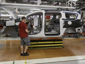 An auto worker works on a 2017 Chrysler Pacifica on the assembly line at the Windsor Assembly Plant.