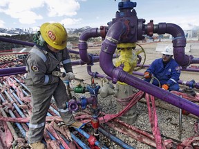 Workers tend to a well head during a fracking operation at an Encana Oil & Gas gas well in Colorado.