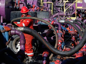 A worker adjusts hoses during a hydraulic fracturing operation at a gas well. "“nearly every fifth barrel of oil and every fourth cubic meter of gas in the world will come from the U.S.," the late Harvard oil expert Leonardo Maugeri declared.