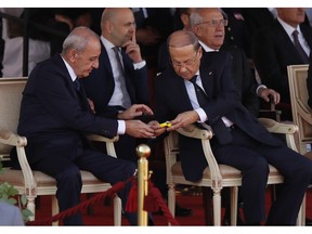 Lebanese President Michel Aoun, center right, gives candy to Lebanese Parliament Speaker Nabih Berri, during a military parade to mark the 75th anniversary of Lebanon's independence from France, in downtown Beirut, Thursday, Nov. 22, 2018. Many anxious Lebanese feel they have little to celebrate: the country's corruption-plagued economy is dangerously close to collapse and political bickering over shares in a new Cabinet is threatening to scuttle pledges worth $11 billion by international donors.