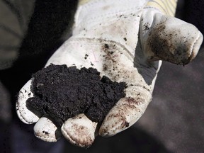 An oil worker holds raw oilsands near Fort McMurray, Alta. A plan hatched by some oil executives calls on Alberta to intervene in the oil market and cut off supply because of historically low prices.
