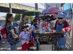 In this Thursday, Nov. 1, 2018, photo, school children gather around street vendors outside their school in Bangkok, Thailand. A report by the United Nations Food and Agricultural Organization released Friday, Nov. 2,  says some 486 million people are malnourished in Asia and the Pacific, and progress in alleviating hunger has stalled.