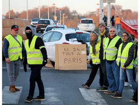 Demonstrators protest in Bayonne, southwestern France, Monday, Nov. 19, 2018. French drivers blocked oil depots and disrupted traffic toward the tunnel beneath the English Channel on Monday as they tried to keep up pressure on President Emmanuel Macron's government to abandon fuel tax hikes. Placard reads " All together in Paris on Nov. 24".