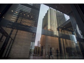The financial district is reflected on the window as business people make their way through the Toronto Dominion Centre in Toronto on Wednesday, June 27, 2018.
