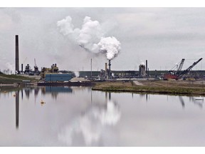 The Syncrude oil sands extraction facility is reflected in a tailings pond near the city of Fort McMurray, Alta. on Sunday, June 1, 2014. The Alberta Energy Regulator says it doesn't agree with a presentation given by a senior executive earlier this year that pegged the cost of cleaning up after the oil and gas industry at $260 billion.