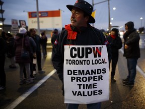 A Canada Post Corp. worker walks the picket line in front of the Gateway Postal facility in Toronto.