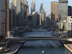 A tram crosses a bridge over a canal that forms the Marina waterfront district of Dubai, United Arab Emirates.