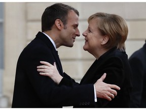 FILE - In this Nov. 11, 2018 file photo, French President Emmanuel Macron hugs German Chancellor Angela Merkel in the courtyard of the Elysee Palace in Paris while marking the 100th anniversary of the end of World War I. Macron and Merkel, both limping in the polls, are looking for common approaches to U.S. President Donald Trump and fixing the flaws in the euro currency. Macron will address the German parliament on Sunday, Nov. 18, 2018.