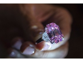 FILE - In this Thursday, Nov. 8, 2018 file photo, a Christie's employee displays an 18.96-carat fancy vivid pink diamond during a preview at Christie's in Geneva, Switzerland.  Christie's sold the "Pink Legacy" diamond at auction Tuesday, Nov. 13 for more than $50 million including fees, saying it's a new world record price per carat for a pink diamond. Christie's said that renowned jeweler Harry Winston was the buyer.