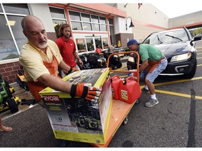 FILE - In this Sept. 10, 2018 file photo, Jim Craig, David Burke and Chris Rayner load generators as people buy supplies at The Home Depot in Wilmington, N.C. Home Depot Inc. reports earnings Tuesday, Nov. 13.