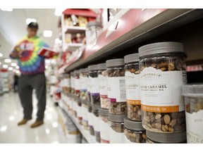 In this Friday, Nov. 16, 2018, photo, a line of mixed treats containers are seen as a shopper pulls an item from the shelf at a Target store in Edison, N.J. Shoppers are spending freely heading into the holidays, but heavy investments and incentives like free shipping by retailers are giving Wall Street pause. Target Inc., Kohl's Corp., Best Buy Co. and TJX Cos. all reported strong sales at stores opened at least a year.