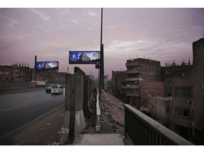 In this Oct. 23, 2018 photo, billboards promoting a new residential housing compound  overlook a crowded run-down neighborhood, on the ring road, in Cairo, Egypt. A city of 20 million people that combines charm and squalor, Cairo may soon witness an exodus by some of its well-heeled residents, state employees and foreign embassies to a new capital, miles from the Nile-side city that has been the seat of power for more than 1,000 years.