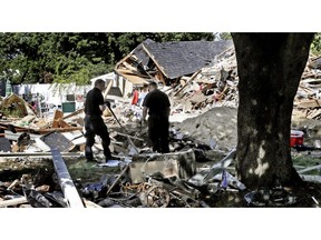 FILE- In this Sept. 21, 2018 file photo, fire investigators pause while searching the debris at a home which exploded following a gas line failure in Lawrence, Mass.  Federal prosecutors have been conducting a criminal investigation into the natural gas explosions and fires that rocked three communities north of Boston in September. NiSource, the parent company of Columbia Gas of Massachusetts, disclosed Thursday, Nov. 1,  it is cooperating with a criminal investigation by U.S. Attorney for Massachusetts Andrew Lelling's office.  The Indiana-based utility made the disclosure in its quarterly financial disclosure report to the U.S. Securities and Exchange Commission.