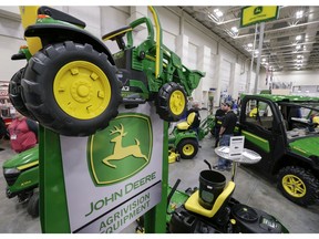 FILE - In this Feb. 23, 2018 file photo, John Deere products, including a toy tractor on the sign, are on display at the "Spring into Spring" home and garden trade show in Council Bluffs, Iowa, John Deere, the maker of agricultural and construction equipment, reported a 46 percent boost in profit to $784.8 million, or $2.42 per share. But earnings, adjusted for pretax gains, came to $2.30 per share, 14 cents short of industry analyst projections, according to a survey by Zacks Investment Research.